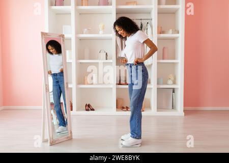 Lateinische Frau in Jeans, die ihr Spiegelbild anlächelt Stockfoto