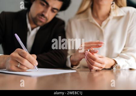 Ein kurzer Schuss von traurigen Ehepaaren, die Dekretpapiere unterzeichnen und sich im Anwaltsbüro am Schreibtisch scheiden lassen. Unglücklicher verheirateter Mann und Frau, die sich scheiden lassen Stockfoto