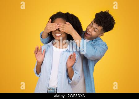 Verspieltes junges Paar mit Mann, der die Augen der Frau von hinten bedeckt Stockfoto