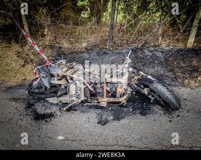 Ausgebranntes gestohlenes Motorrad am Straßenrand. Stockfoto