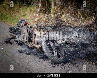 Ausgebranntes gestohlenes Motorrad am Straßenrand. Stockfoto