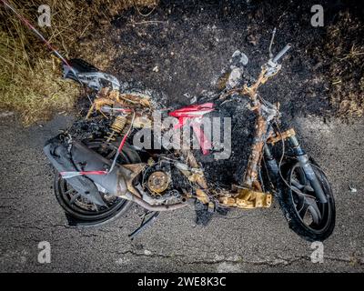 Ausgebranntes gestohlenes Motorrad am Straßenrand. Stockfoto