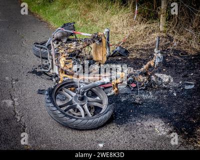 Ausgebranntes gestohlenes Motorrad am Straßenrand. Stockfoto