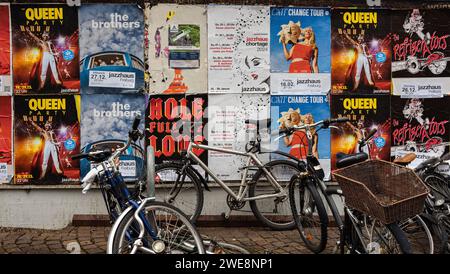 Freiburg im Breisgau, Deutschland - 28. Dezember 2023: Eine Wand mit Werbeplakaten und Konzertdurchsagen. Fahrräder stehen vor dem Hotel Stockfoto