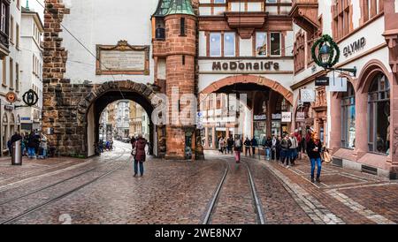 Freiburg im Breisgau, Deutschland - 28. Dezember 2023: Mittelalterliches Stadttor mit in Freiburg im Breisgau - urbanes Leben. Stockfoto