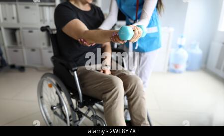 Mann im Rollstuhl arbeitet seine Hand mit Hantel aus Stockfoto