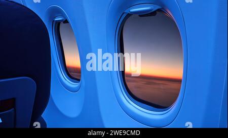 Flugzeugfenster mit Blick auf den Sonnenuntergang in Orange. Stockfoto