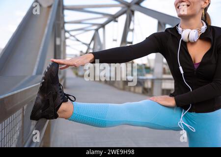 Aktive Läuferin mit lächelndem Lächeln wärmt sich beim Laufen oder beim Ausdauertraining auf. Stockfoto