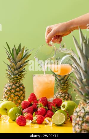 Frischer kalter Saft mit Vitaminen und Aromen von Ananas, Apfel, Erdbeere und Limette auf grünem Hintergrund Stockfoto