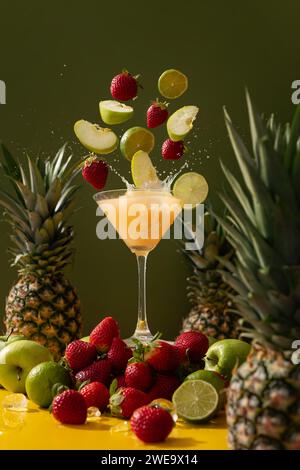 Frischer kalter Saft mit Vitaminen und Aromen von Ananas, Apfel, Erdbeere und Limette auf grünem Hintergrund Stockfoto