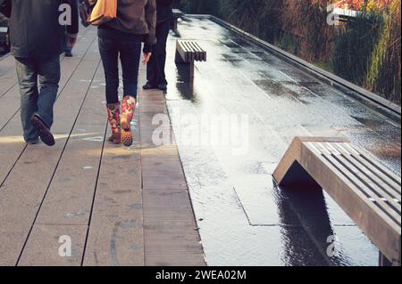 Modische junge Leute, die nach Morgenregen auf der High Line in New York City laufen. Stockfoto
