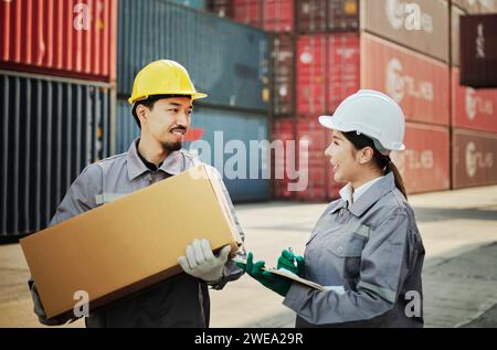 Teamingenieur Mitarbeiter halten Kartonverpackungen, um die Produktqualität zu überprüfen. Am Containerladeplatz Stockfoto