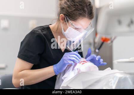 Der Zahnarzt untersucht Mund und Zähne des Patienten mit einem Zahnforscher. Stockfoto