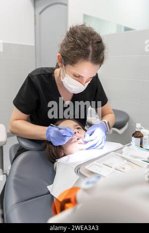 Ein pädiatrischer Zahnarzt führt vor der Kariesbehandlung eine zahnärztliche Untersuchung durch. Stockfoto