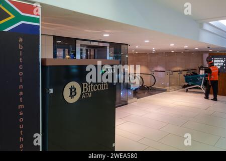 Bitcoin Geldautomat befindet sich in einem modernen Einkaufszentrum mit Menschen und südafrikanischer Flagge im Hintergrund Stockfoto