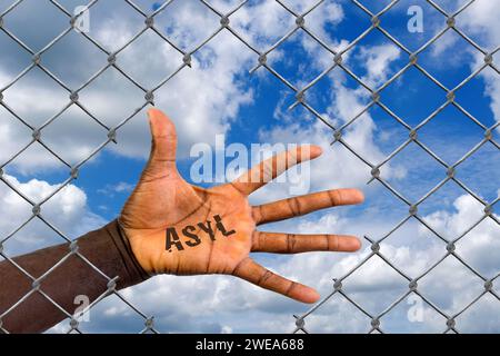 Die Hand eines Ausländers hinter einem Maschendrahtzaun, Loch, Schlupfloch, Hilfe, Flüchtling, Asyl, Migrant, Migration, Ausländer, Schwarz, Afrikaner Stockfoto