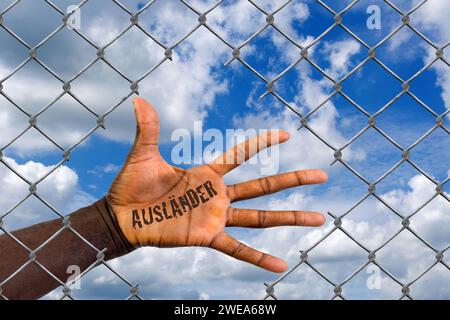 Die Hand eines Ausländers hinter einem Maschendrahtzaun, Loch, Schlupfloch, Hilfe, Flüchtling, Asyl, Migrant, Migration, Ausländer, Schwarz, Afrikaner Stockfoto