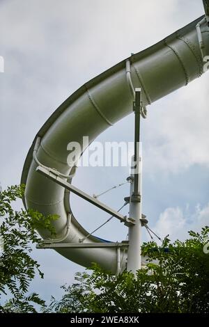 Geschwungene Riesenwasserrutsche mit grünem Laub - von Grund auf Blick Stockfoto