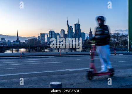 Skyline der Innenstadt von Frankfurt am Main, E-Scooter auf der Floßbrücke, Dämmerung, Main, Winter, Hessen, Deutschland Stockfoto