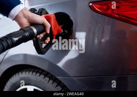 Nahaufnahme des männlichen Handbetanks des schwarzen Luxusautos an der Tankstelle, Kopierraum Stockfoto