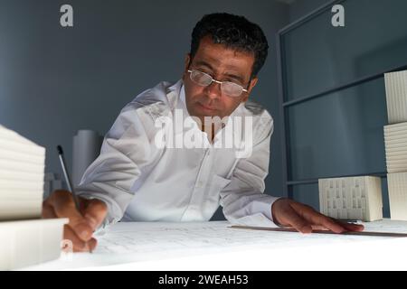 Porträt eines Reifen Architekten, der eine Brille trägt und Pläne am Arbeitsplatz im Büro und im Kopierraum entwirft Stockfoto