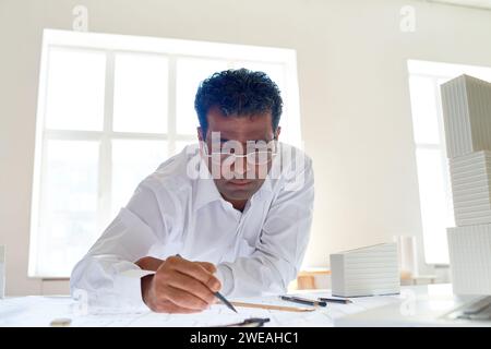 Porträt eines männlichen indischen Architekten, der Skizzen am Schreibtisch im Büro, Kopierraum zeichnet Stockfoto