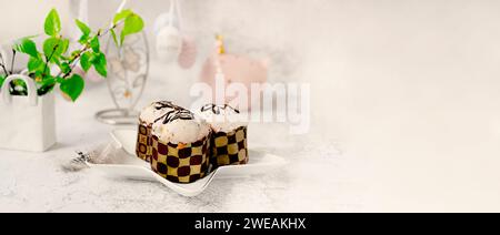 Osterdekor. Osterstillleben mit bunten Osterkuchen, Eiern auf Kaninchen-Dessertteller. Traditionelles Ostergeschenk auf festlichem Tisch, dekoriert mit spr Stockfoto