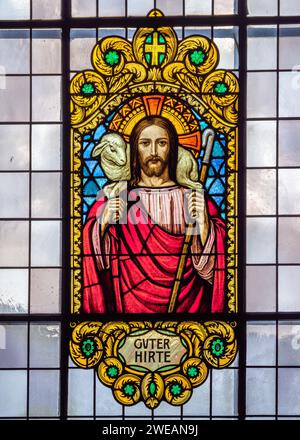 Zermatt, Schweiz - 23. September 2023: Buntglasfenster mit dem Bild des Christus, des Guten Hirten in der Pfarrkirche St. Maurice Stockfoto