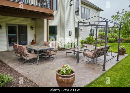 Elegante Terrasse mit Steinpflaster und Essgarnitur im Freien und Schaukelsitz Stockfoto