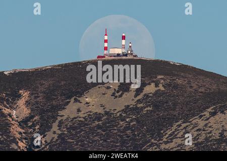 Madrid, Spanien. Januar 2024. Ein fast Vollmond des Januar (bekannt als Wolf Moon) ragt über dem 1959 eingeweihten spanischen Fernsehzentrum in Bola del Mundo in Navacerrada auf einer Höhe von 2.262 Metern auf. Quelle: Marcos del Mazo/Alamy Live News Stockfoto