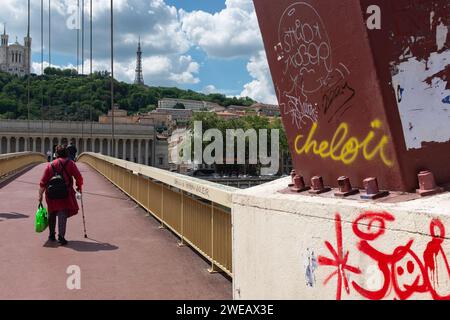 Lyon, Frankreich, 2023. Eine Dame überquert die Brücke Palais de Justice mit der Basilique Notre-Dame de Fourvière und der Tour Métallique im Hintergrund Stockfoto