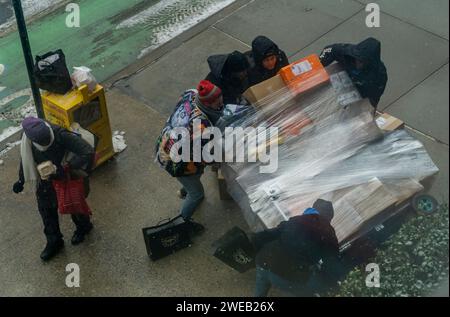 Ein Amazon-Mitarbeiter bittet einen Passanten um Hilfe, um seinen gestürzten Wagen am Freitag, den 19. Januar 2024, vor einem Wohnhaus in New York zu rechtfertigen. (© Richard B. Levine) Stockfoto