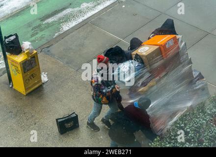 Ein Amazon-Mitarbeiter bittet einen Passanten um Hilfe, um seinen gestürzten Wagen am Freitag, den 19. Januar 2024, vor einem Wohnhaus in New York zu rechtfertigen. (© Richard B. Levine) Stockfoto