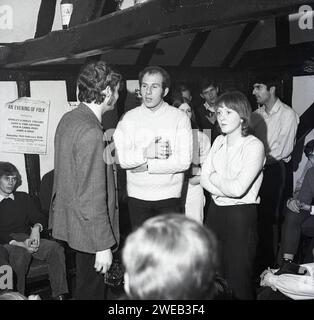 1970, historisch, versammelten sich die Menschen in einem Raum in einem alten, hölzernen Pub, dem Red Lion, in der Stevenage Old Town, zu einer Folk-Musik-Jam-Session. Poster an der Wand sagt, an Abend of Folk im Stevenage College of Continuing Education, 14. Februar 1970. Stockfoto