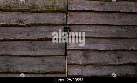 Ein Holzzaun und ein Tor aus Dielen mit Schloss. Holzzaun mit Türen. Stockfoto