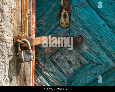 Nahaufnahme der Gleitschraube. Altes, rostiges Schloss und Verriegelung an abgenutzter grüner Holztür. Stockfoto