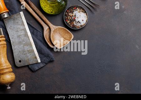 Kulinarisches Essential: Diverse Kochutensilien und Gewürze auf Steintisch. Flache Ladefläche mit Kopierraum Stockfoto