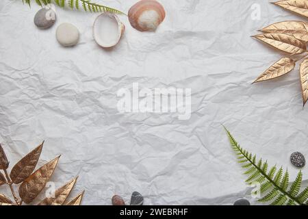 Sommerstimmung mit Muscheln und Steinen vor einem Hintergrund aus geknittertem Papier. Kopierbereich. Stockfoto