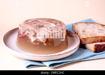 Gelee mit Fleisch, Rindfleisch Aspik, traditionelles Gericht. Portion auf Teller mit hausgemachtem Brot. Stockfoto