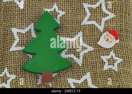 Kleiner hölzerner Weihnachtsbaum und Kopf des Weihnachtsmanns auf einem Jutesack mit Sternen bedruckt Stockfoto