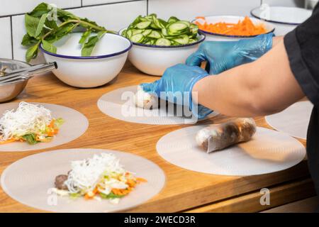 Der Koch bereitet Frühlingsrollen auf einem hölzernen Schneidebrett in der Küche des Restaurants zu. Stockfoto