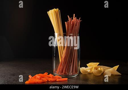 Dieses lebendige Bild zeigt ein fesselndes Stillleben-Arrangement aus verschiedenen Arten italienischer Pasta, gut beleuchtet und fachmännisch im Dunkeln festgehalten Stockfoto