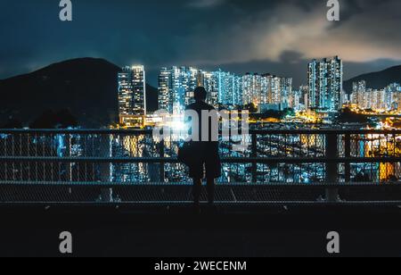 Nächtliche Silhouette einer Person vor modernen modernen Wolkenkratzern in der Marina mit Piers und Yachten in Aberdeen, Hongkong Stockfoto