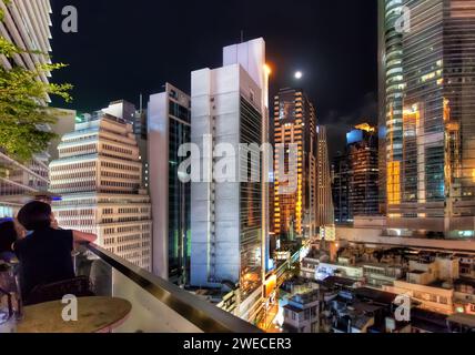 Abendliche Cocktails in der Dachbar mit modernen asiatischen Wolkenkratzern und Mondlicht in Hongkong Stockfoto