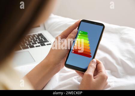 Energieeffizienz. Frau, die ein Smartphone benutzt, mit farbenfroher Bewertung auf dem Display, Nahaufnahme Stockfoto