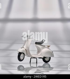 Foto einer alten Miniatur-Vespa, die auch Roller genannt wird. Fotografiert mit hellem Hintergrund, um das weiße Vespa-Objekt zu isolieren Stockfoto