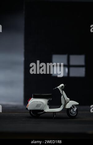 Foto einer alten Miniatur-Vespa, die auch Roller genannt wird. Fotografiert mit einem nicht so hellen Hintergrund, um das weiße Vespa-Objekt zu isolieren Stockfoto