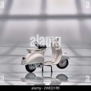 Foto einer alten Miniatur-Vespa, die auch Roller genannt wird. Fotografiert mit hellem Hintergrund, um das weiße Vespa-Objekt zu isolieren Stockfoto