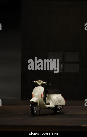 Foto einer alten Miniatur-Vespa, die auch Roller genannt wird. Fotografiert mit einem nicht so hellen Hintergrund, um das weiße Vespa-Objekt zu isolieren Stockfoto