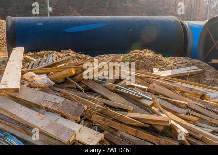 Schnitte von Holz, die willkürlich auf dem Boden vor großen Industrierohren aus Stahl auf der Berghütte verstreut sind Stockfoto